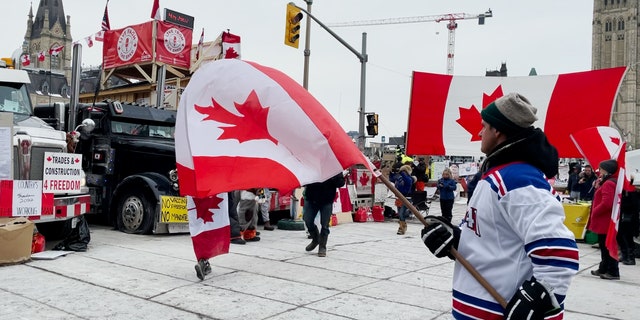 オタワのフリーダムキャラバンの20日目に男がカナダ国旗を振る。