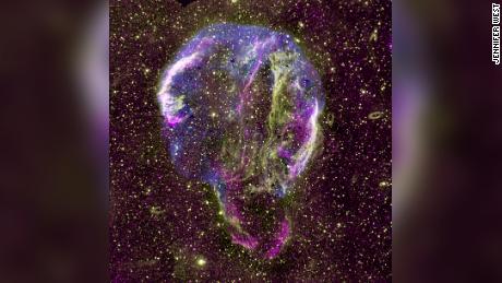 天の川銀河に残っているシグナスリングの超新星残骸のラジオ（紫）、UV（黄色）、X線（青）の画像が表示されています。 