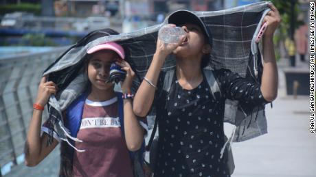ムンバイの灼熱の午後の暑さの中で歩いたり水を飲んだりするとき、女の子は頭を覆います。