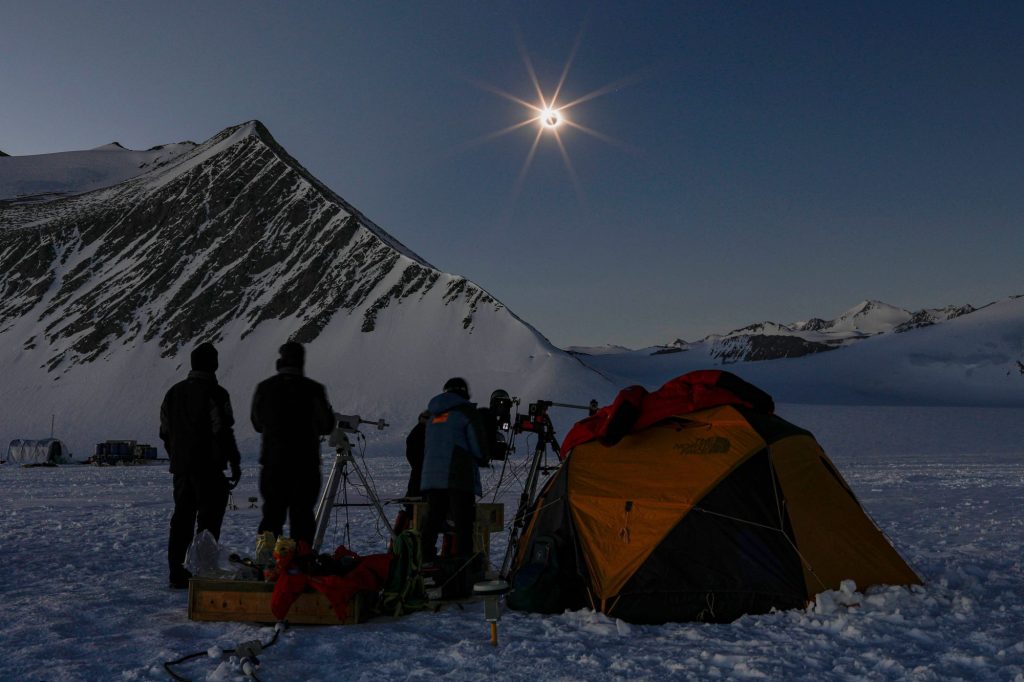 Imagen Chileによって投稿されたこの画像は、2021年12月4日に南極のユニオン氷河からの日食を見ているチリと米国の科学者を示しています。