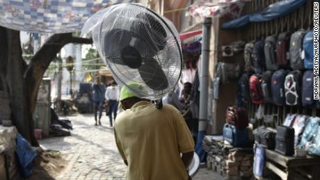 インドのコルカタで猛暑の最中に男性が扇風機を持っています。
