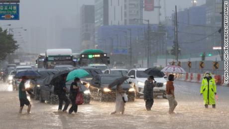 8月9日、ソウルの金浦で浸水した道路を横断する歩行者。