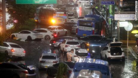 8 月 8 日、韓国のソウルで大雨が降る中、浸水した地域の道路に放置された車が埋め尽くされている。