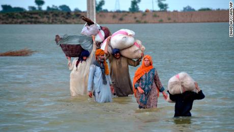 8 月 24 日、パキスタン南西部のバロチスタン州にあるジャファラバード地区の浸水した地域を歩く避難民の家族。