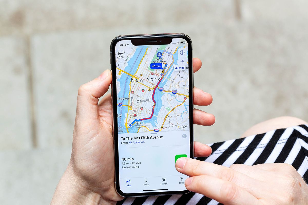 Apple Maps でニューヨーク市のある場所への道順を示している iPhone を持っている人。