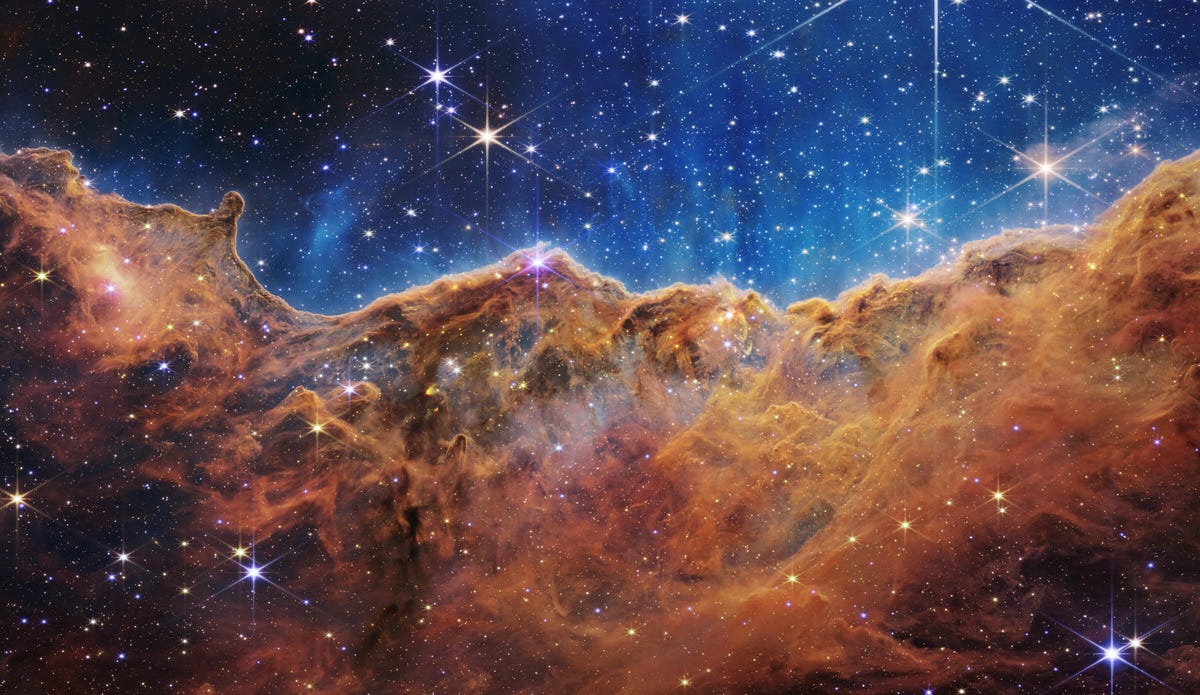 カリーナ星雲: さびた青銅色のガス雲の上の藍色の背景に輝く星