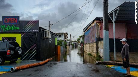 ハリケーン・フィオナが通過した後、プエルトリコのカターノのフアナ・マトス地区で浸水した通りを見る男性。 