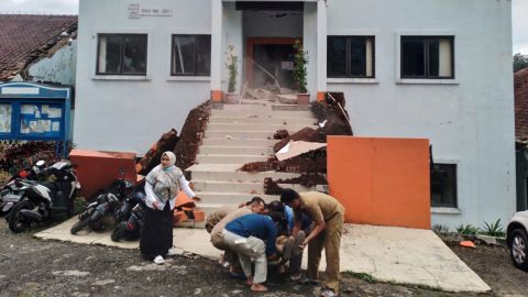チアンジュールの市職員は、地震の余波で負傷した同僚を避難させます。