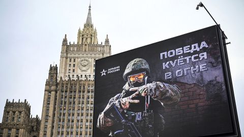 メッセージを表示する看板の後ろにロシア外務省の建物が見える 