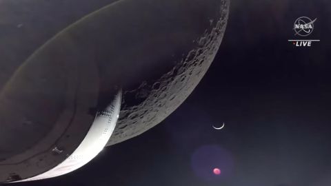 オリオン カプセルは、太陽に照らされた三日月として地球を背景に、月の表面のビューをキャプチャします。